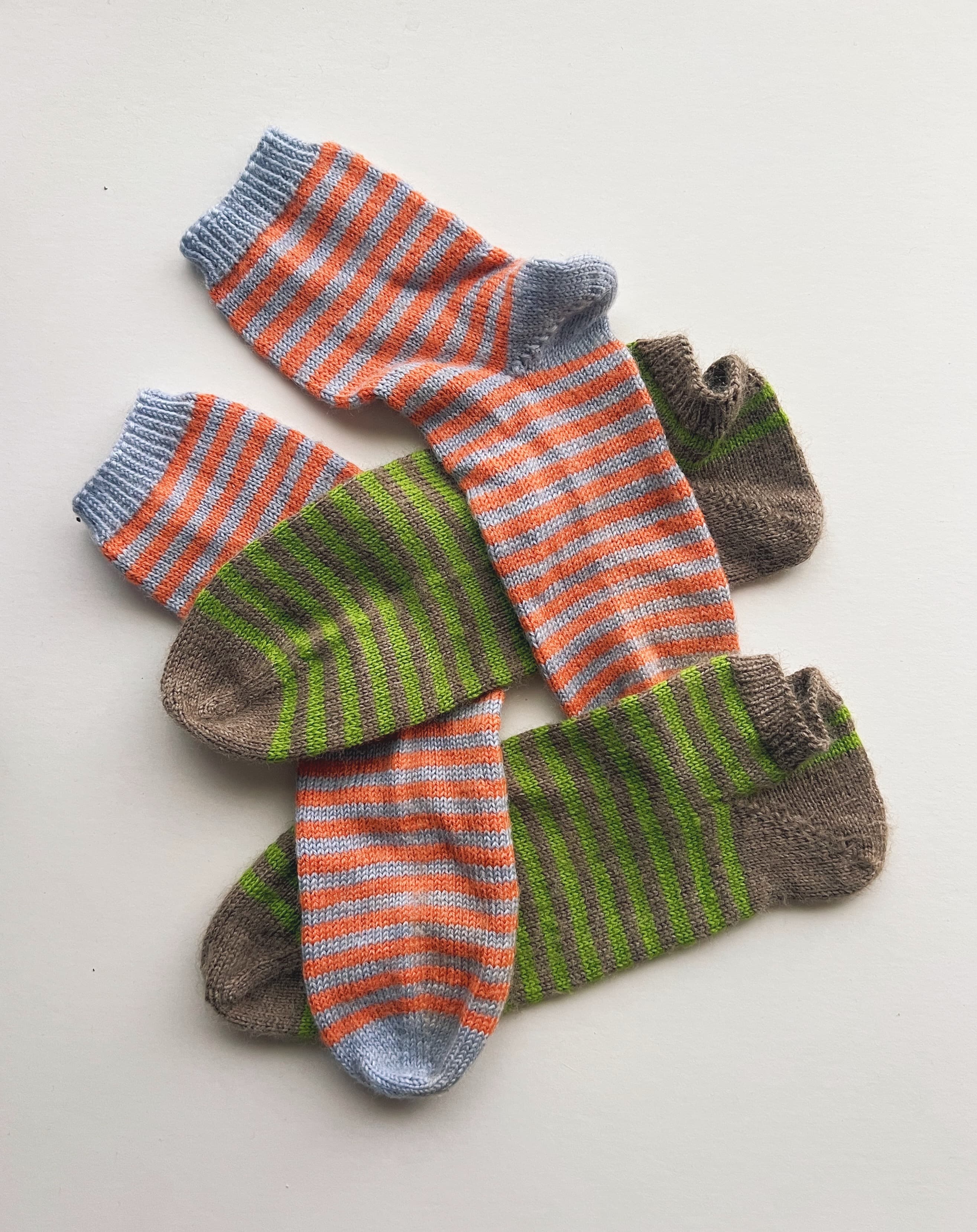 Two pairs of striped socks, one orange and light blue, one green and brown